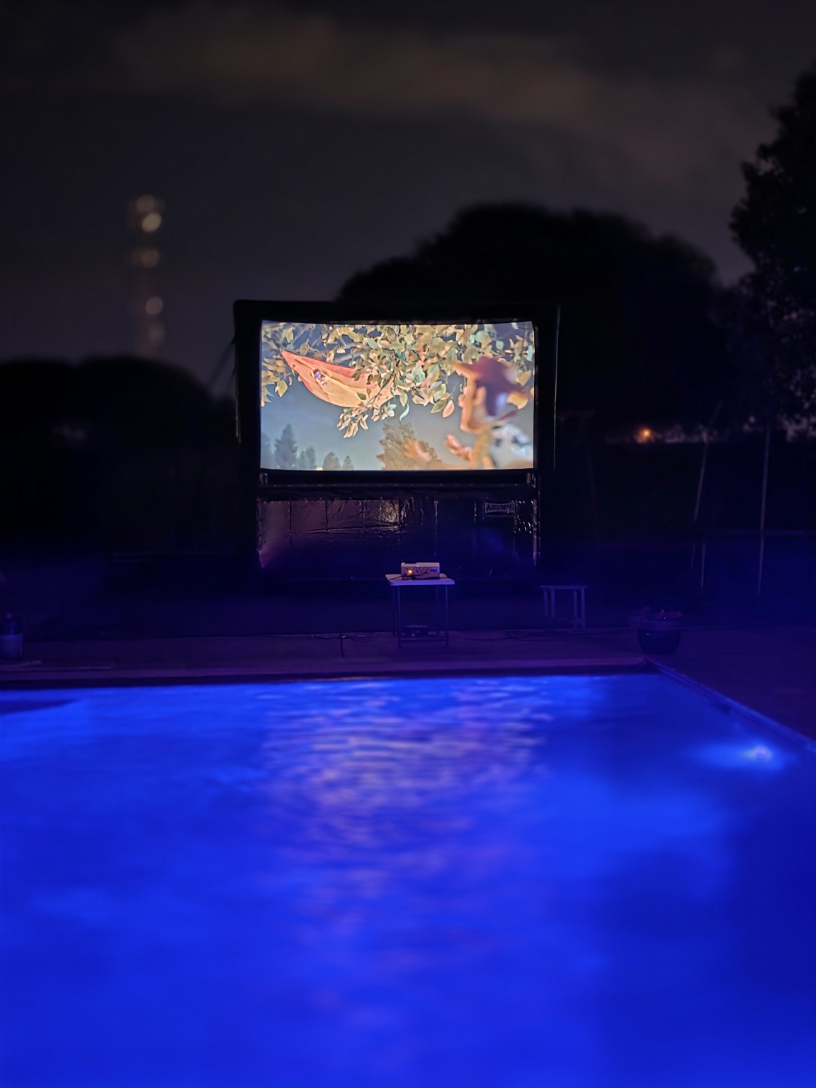 806 Big Screen’s 12-foot AIRSCREEN airtight screen showing a movie beside a blue-lit pool